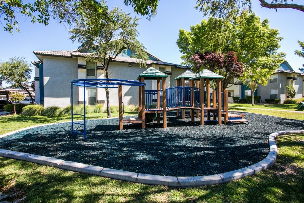 a playground with a swing set in front of a house