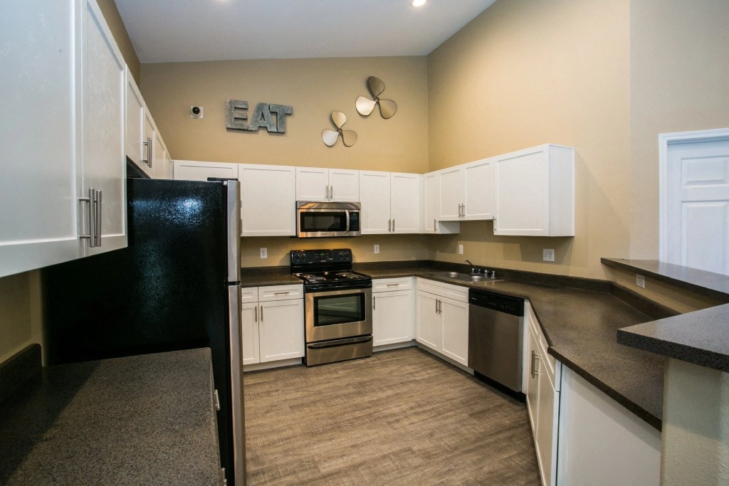 a kitchen with white cabinets and black appliances and a counter top