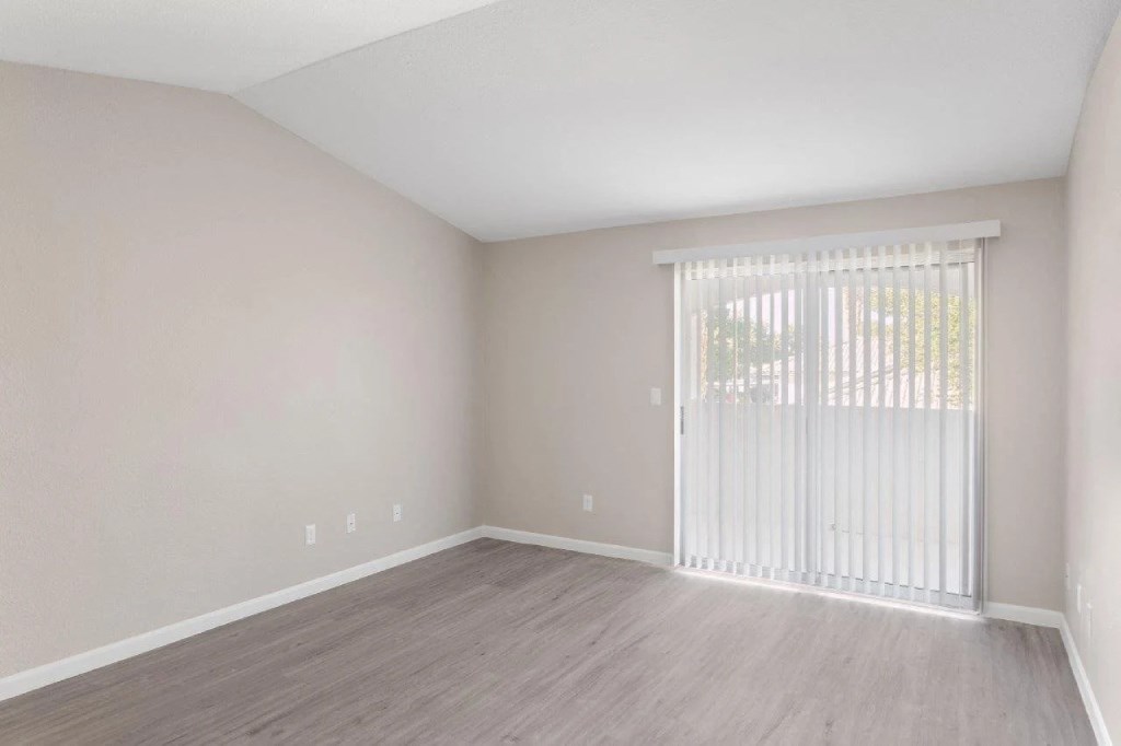 an empty living room with a large window and a sliding glass door