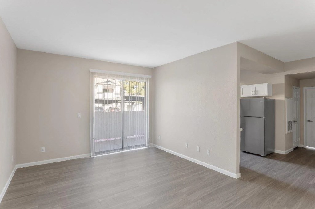 the living room of an apartment with a refrigerator and a sliding glass door