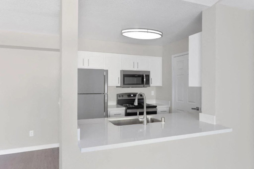 an empty kitchen with a sink and a refrigerator