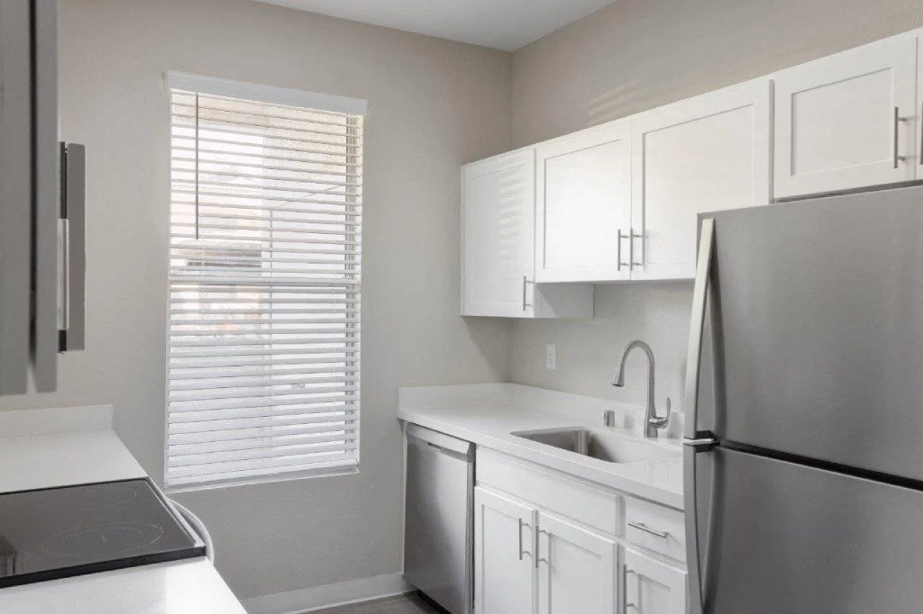 a kitchen with white cabinets and a stainless steel refrigerator