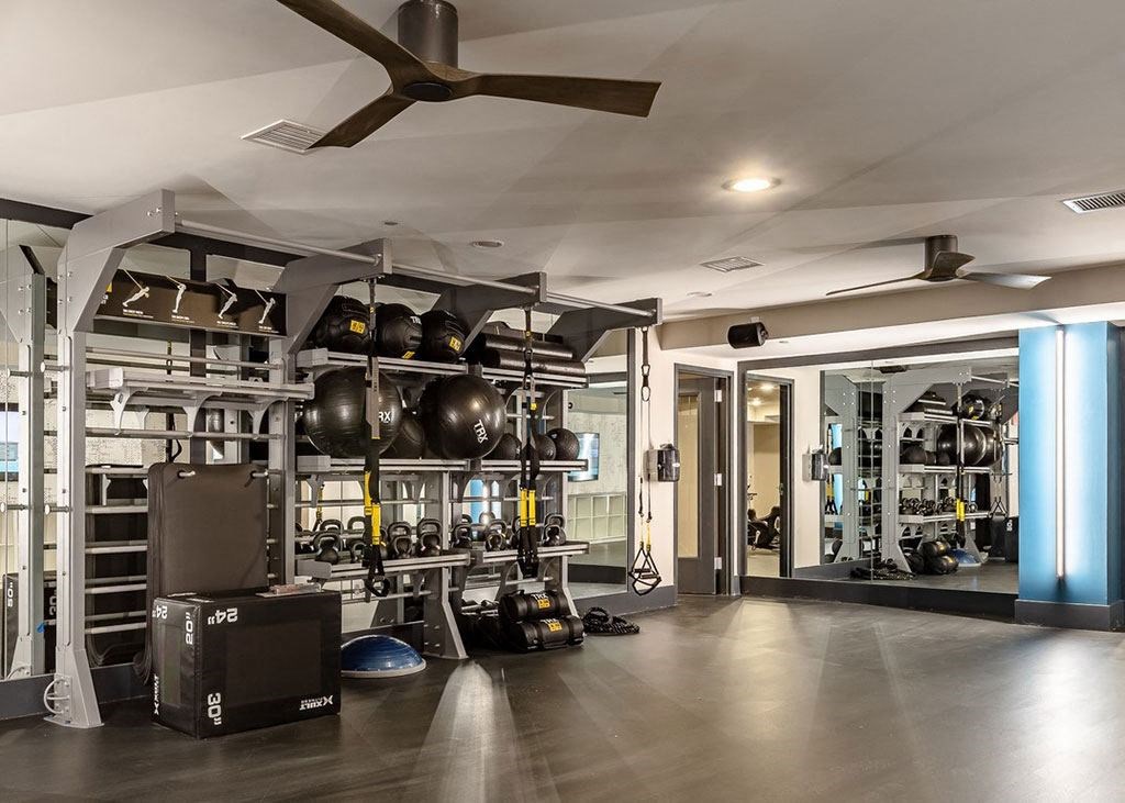 a gym with a lot of equipment and a ceiling fan