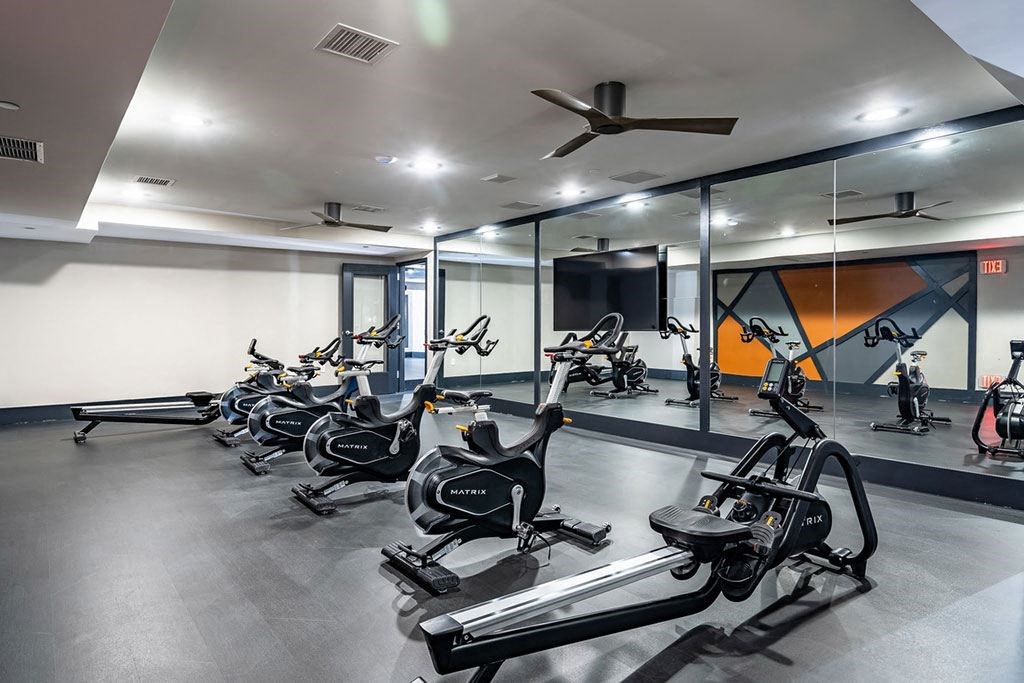 a gym with exercise bikes and a ceiling fan