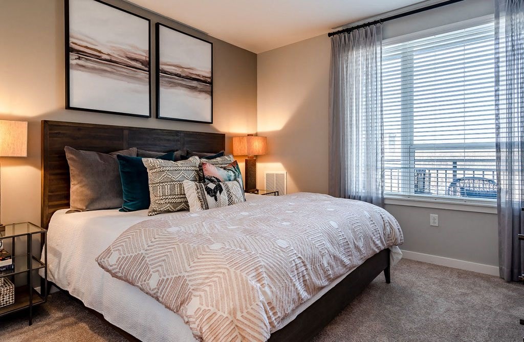 King of Prussia PA Apartments - SKYE 750 - Bedroom with Premium Carpeting, a Large Window, and Modern Furniture