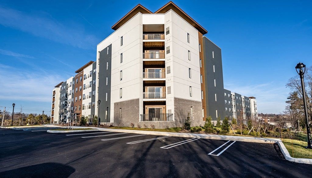 a large apartment building on the corner of a parking lot