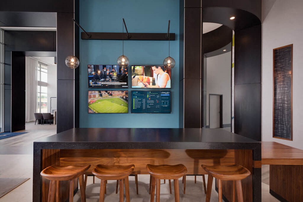 a bar with wooden stools and a wall mounted tv