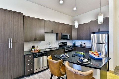 a kitchen with stainless steel appliances and a island with chairs
