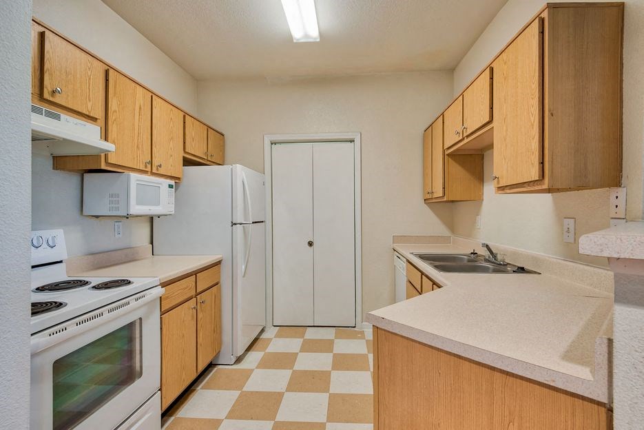 Beaumont, TX Apartments – Breakwater Bay - Kitchen with tile flooring, stainless steel sink, plenty of cabinets for storage, oven/stove top, fridge, and pantry