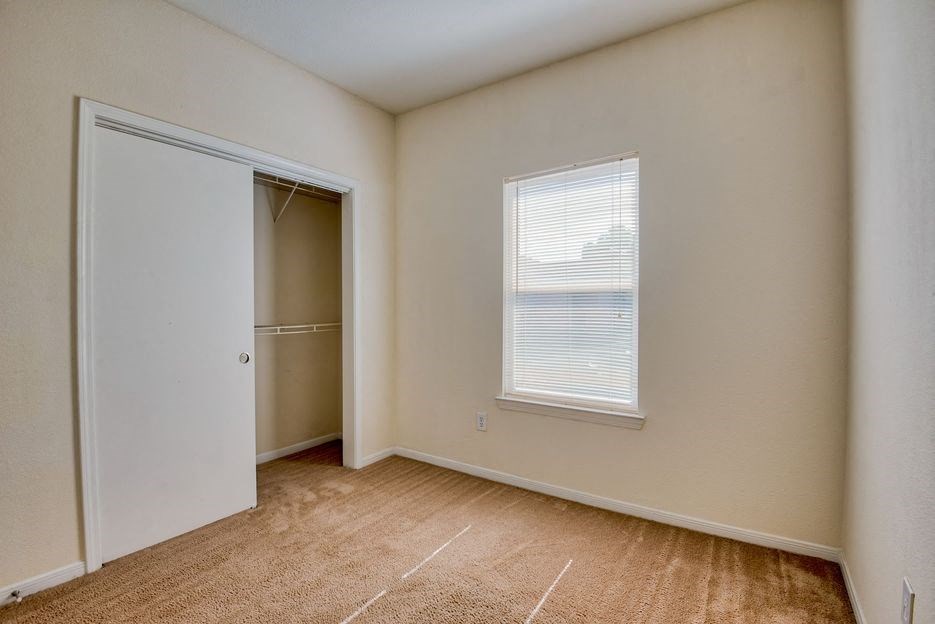 Apartments In Beaumont, TX for Rent – Breakwater Bay - Bedroom with plush carpet, closet for storage, and window with coverings