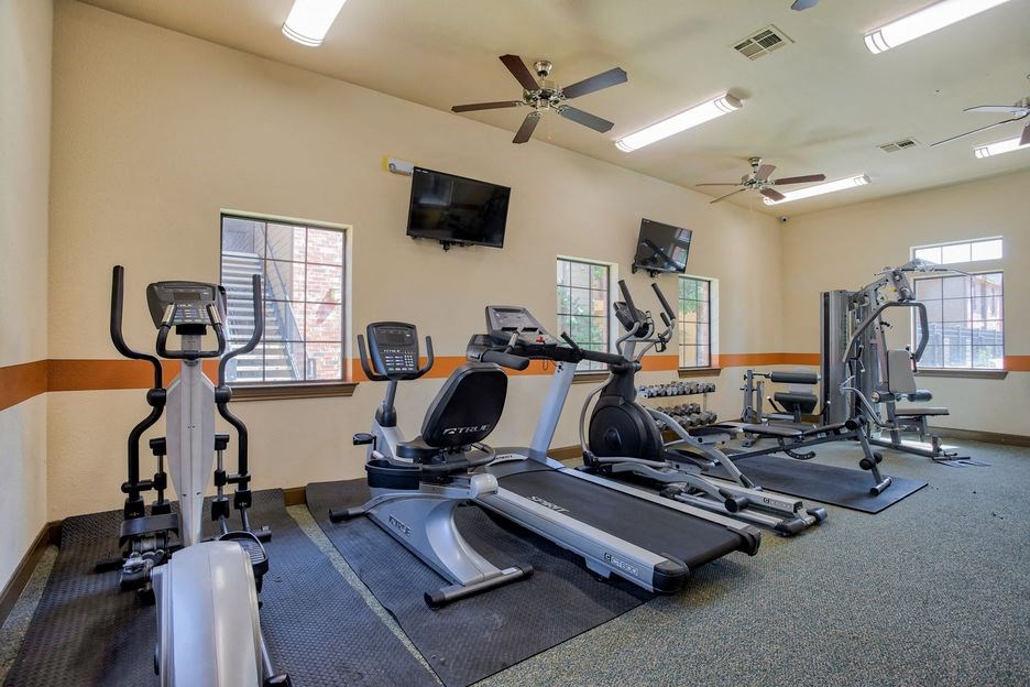 gym with lifting equipment and cardio equipment with windows