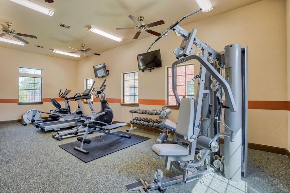 gym with lifting equipment and cardio equipment with windows