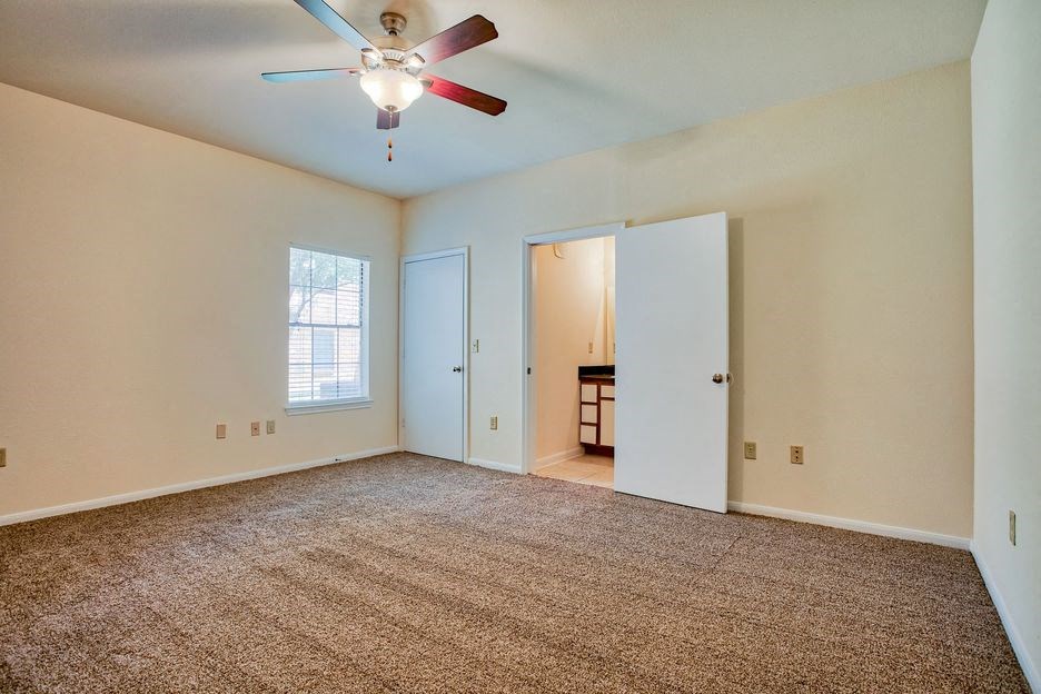 bedroom with carpet and door and window and ceiling fan