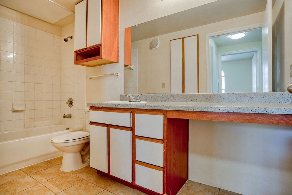 bathroom with mirrors and tile floor and cabinets and mirror and bathtub