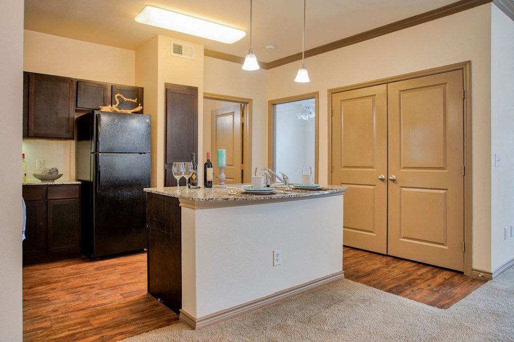 Kitchen with wood floors and black appliances and wood cabinets and stainless steel sink