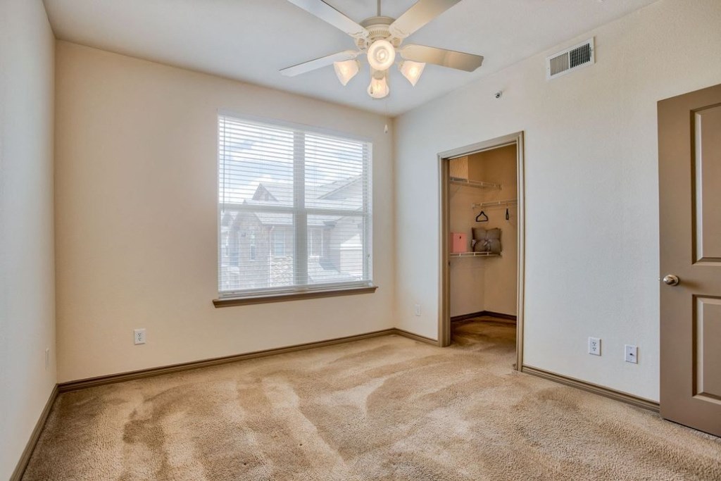 Bedroom with carpet and ceiling fan and windows with blinds and doors