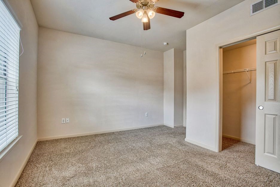 Bedroom with carpet, walk in closet, ceiling fan, and window with blinds