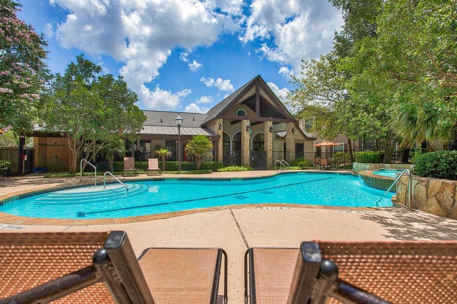 Mission oaks pool surrounded by trees and beach chairs and club house
