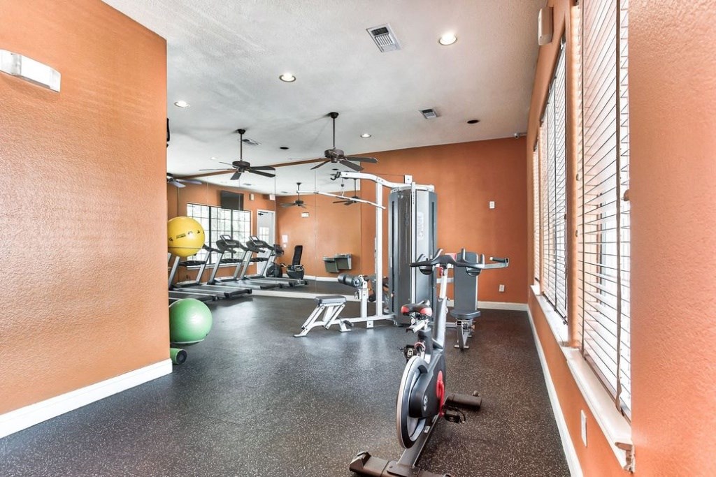 Fitness center with large windows and cardio equipment and ceiling fan