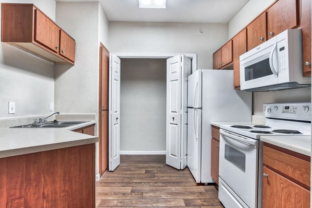 Kitchen with white appliances and wood cabinets and wood floors