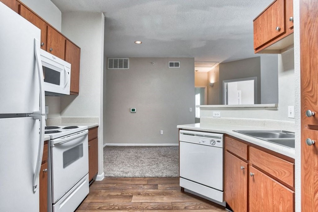 Kitchen with white appliances and wood cabinets and wood floors
