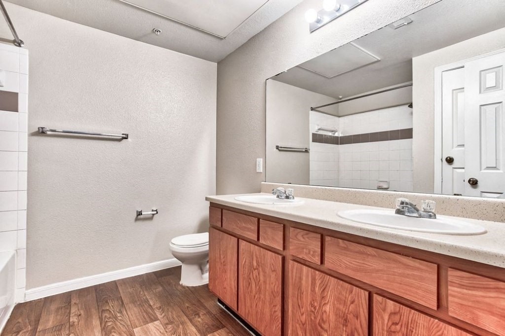 Bathroom with double vanity and large window and toilet and bathtub