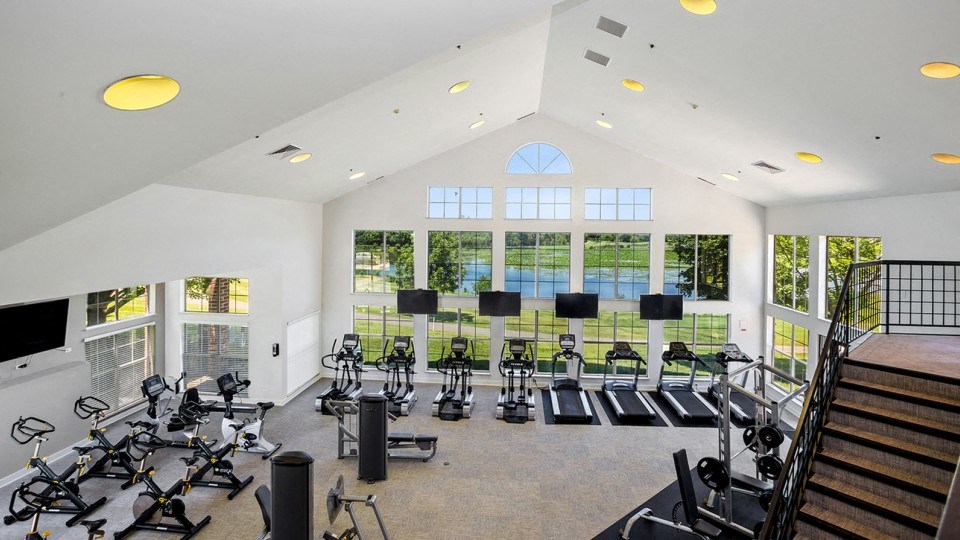 a gym with cardio machines and windows in a large building
