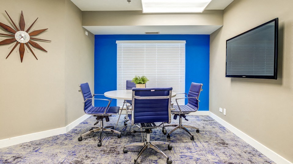 a conference room with a table and chairs and a television