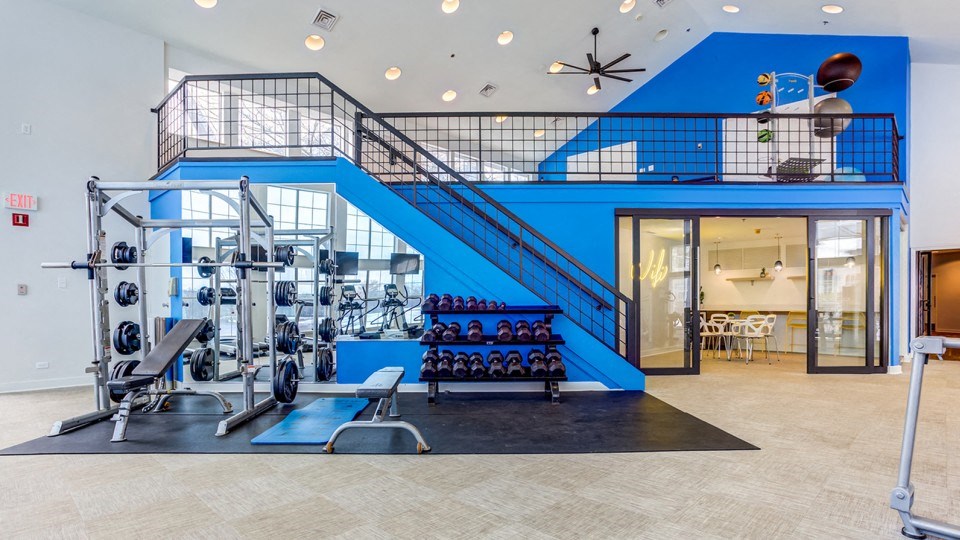 a gym with a blue staircase and weights and cardio equipment
