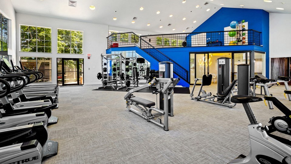 a gym with cardio equipment and a blue staircase
