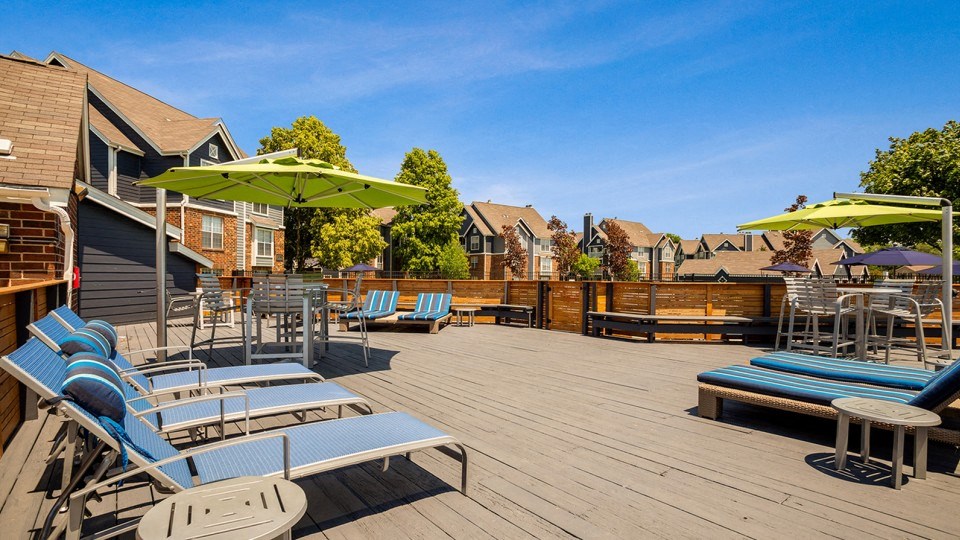 the back deck of a house with lounge chairs and umbrellas