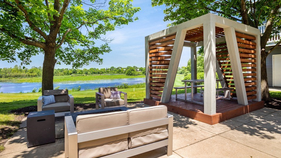a covered patio with furniture and a river in the background