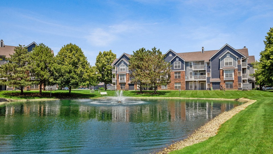 large pond with fountain in front of apartment buildings on a sunny day