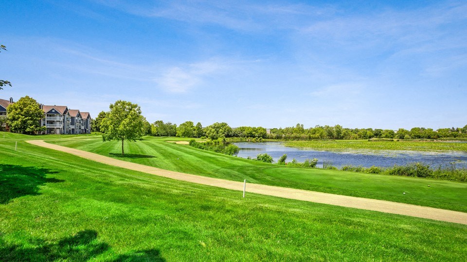 a golf course with a body of water and houses in the background
