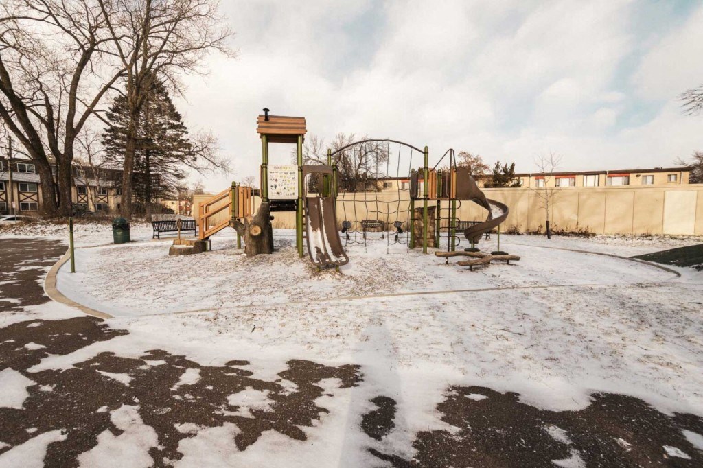 a playground covered in snow next to a fence