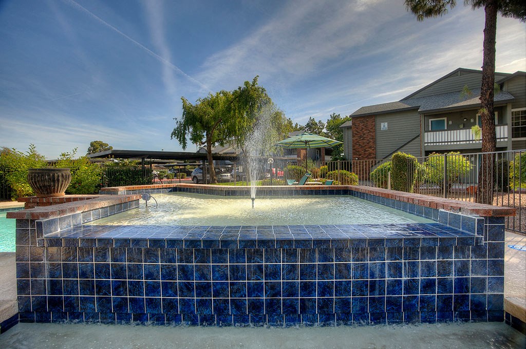 a pool with a fountain in front of a house