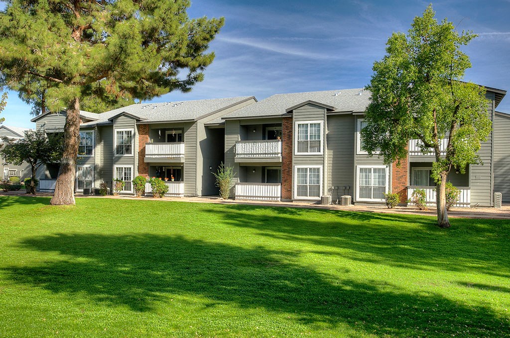 an apartment building with green grass and trees
