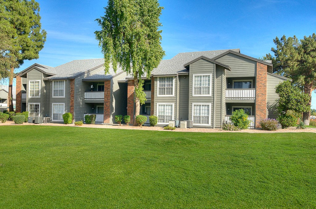 an apartment building with green grass in front of it