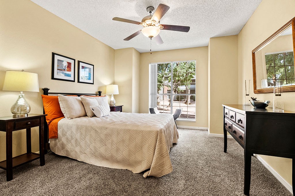 One and Two BR Apartments in North Phoenix, AZ - Cobblestone - A Bright And Spacious Bedroom With Plush Carpeting, A Ceiling Fan, And A Large Window For Natural Light