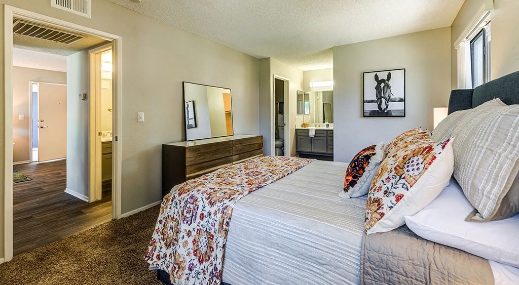 Two-Bedroom Apartments in Ontario, CA - Veranda Ontario - Bedroom with Bathroom Access, Decorative Bedding, and Wooden Dresser