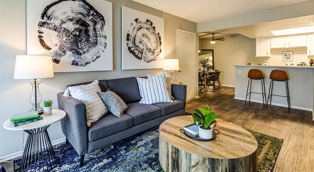 Apartments for Rent in Ontario, CA - Veranda Ontario - Living Room with Carpet Flooring, Grey Couch, Wood Carved Coffee Table, and Blue Area Rug