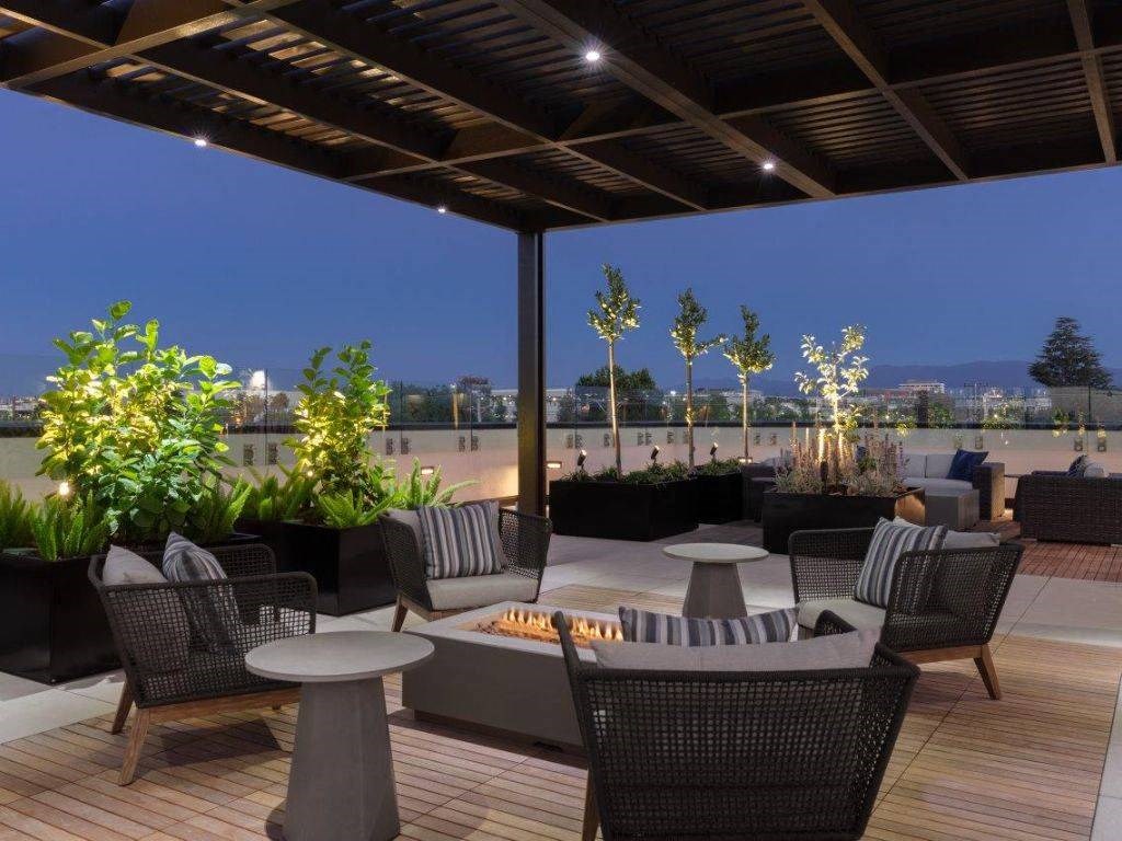 a rooftop patio with tables and chairs and a fire pit