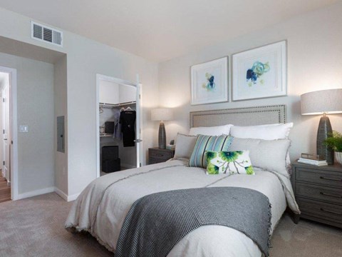 Apartments for Rent in Santa Clara, CA - Santana Terrace Apartments - Bedroom With Upholstered Bed, Nightstands, Lamps, Oversized Closet, Framed Artwork, and Carpeted Flooring.