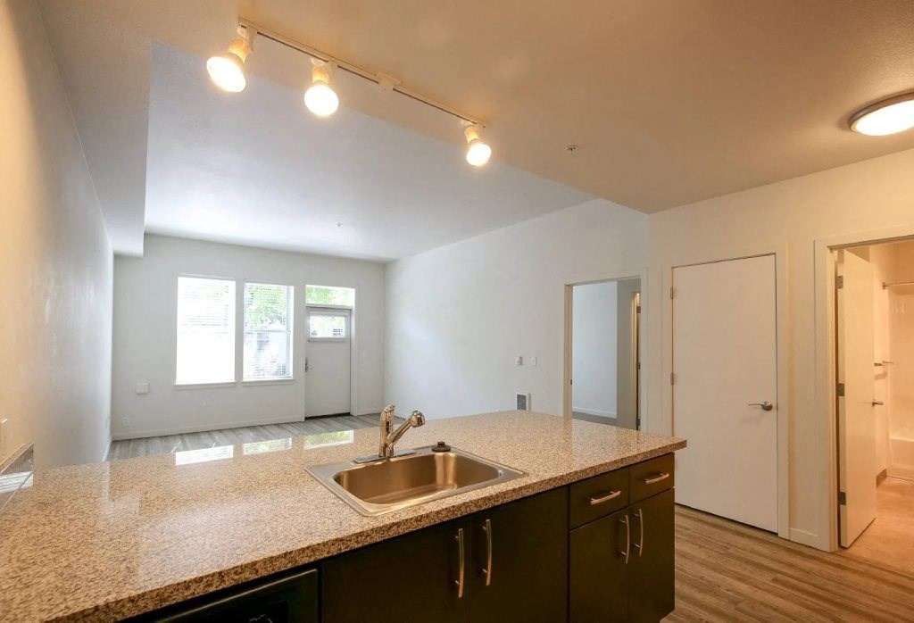 an empty kitchen with a sink and a door to a living room