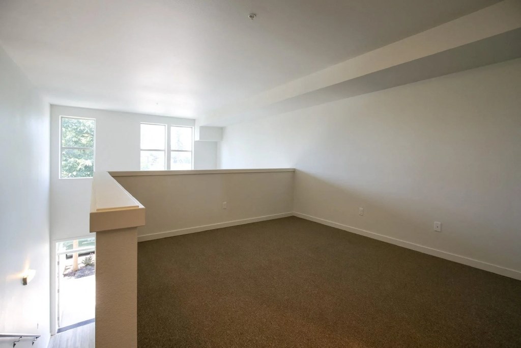 the living room of an empty home with white walls and carpet
