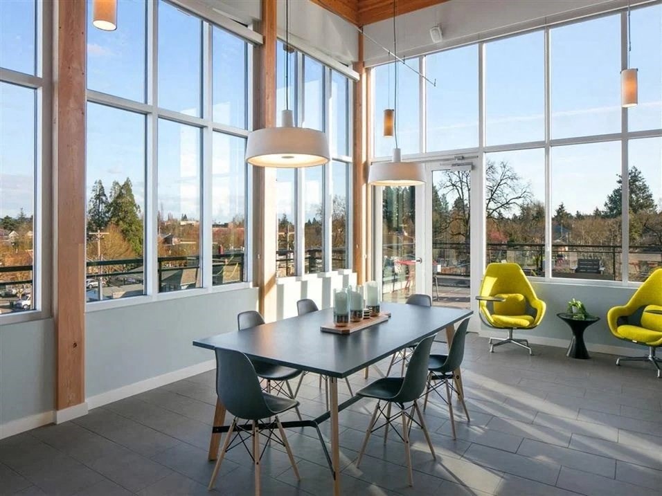 a dining area with a table and chairs in front of a wall of windows