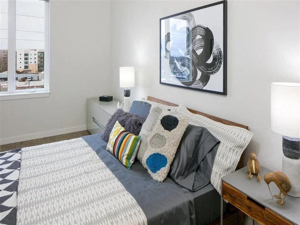 Pet-Friendly Apartments in Beaverton, OR - Westline - Bedroom with Vinyl Hardwood Flooring, Bed, Nightstands with Lamps, Wall Art, and Spacious Window.