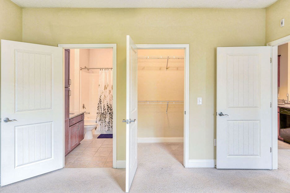two open doors leading to a bathroom and large walk in closet