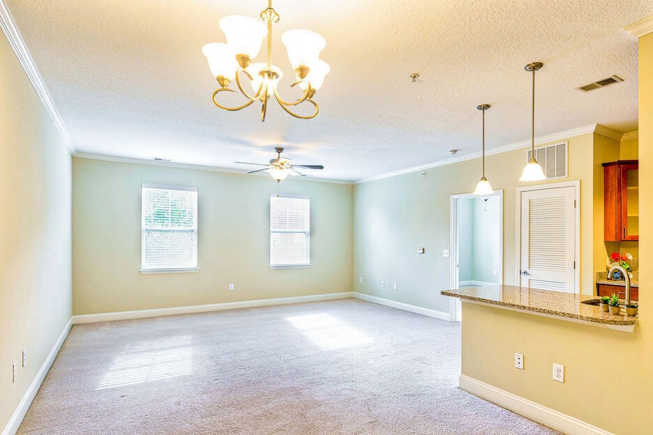 large open living room with nine foot ceilings, two windows, ceiling fan, and overhead lighting