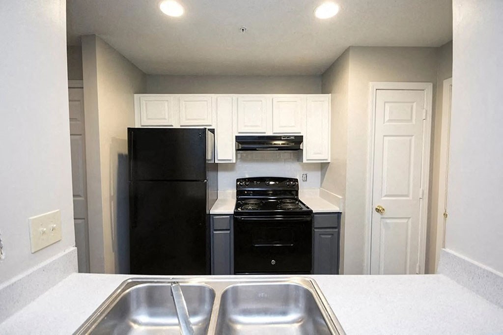 a kitchen with a sink and a black refrigerator